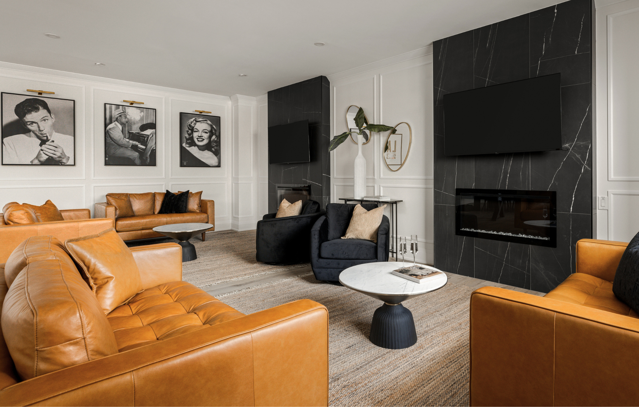 Stylish lounge with tan leather seating, black armchairs, and iconic black-and-white photographs, creating a retro-modern vibe.
