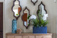 cascading mirror wall display over a console. wood sculpture features